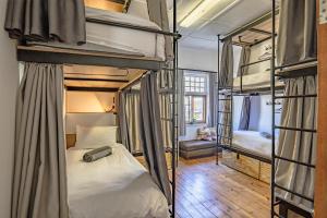 a bedroom with three bunk beds in a room at Adamastor Backpackers in Muizenberg