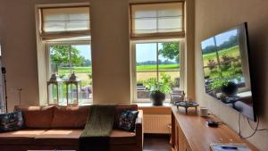 a living room with a couch and a large window at Landhuis onder de lindeboom in Losser