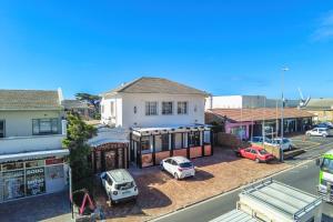 a white house with cars parked in a parking lot at Adamastor Backpackers in Muizenberg