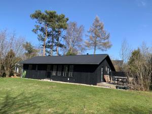 a black building with a bench in a field at Charming Holiday Home At Sought-After Tisvilde in Vejby