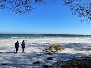 two people standing on the beach looking at the ocean at Holiday Apartment In Peaceful Surroundings in Neksø