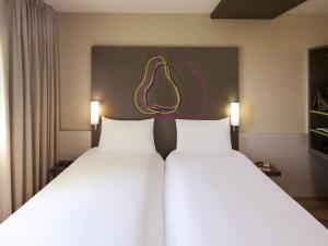 two white beds in a hotel room with a picture of a lemon at Hotel Ibis Styles Lleida Torrefarrera in Lleida +100 photos