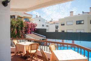 a balcony with tables and chairs and a pool at Estoril Guest Palace in Estoril