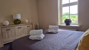 a bedroom with towels on a bed with a window at Landhuis onder de lindeboom in Losser