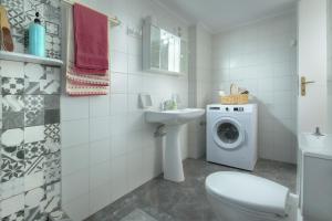 a bathroom with a toilet sink and a washing machine at StayinPyrgi in Pyrgi