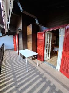 a patio with a white table and red doors at Apartment Pineta Alben 2 in Serina