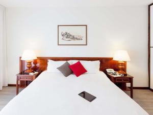 a bedroom with a large white bed with two lamps at Aparthotel Adagio Rome Vatican in Rome +52 photos