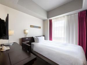 a bedroom with a bed and a desk and a window at ibis Styles Kyoto Station in Kyoto +58 photos