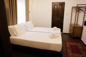 two beds in a room with white sheets and pillows at Moin Moin Boutique Hotel in Berat