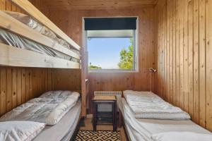 zwei Etagenbetten in einem Holzzimmer mit Fenster in der Unterkunft Charmantes Backsteinhaus Mit Sauna Und Fjordblick in Ørsted