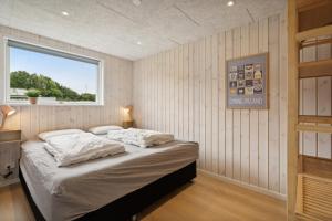 ein Schlafzimmer mit einem Bett in einem Zimmer mit Fenster in der Unterkunft Schönes, Neues Haus Am Meer in Aabenraa