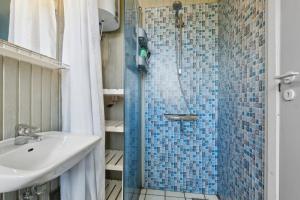 ein Badezimmer mit Waschbecken und Dusche mit blauen Fliesen in der Unterkunft Charmantes Backsteinhaus Mit Sauna Und Fjordblick in Ørsted