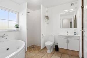 a bathroom with a tub and a toilet and a sink at Cozy Central House Near The Sea in Brenderup +31 photos