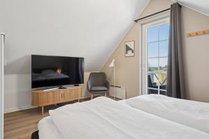 a bedroom with a bed and a tv and a chair at Cozy Central House Near The Sea in Brenderup