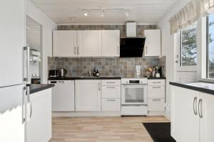 a white kitchen with white cabinets and appliances at Cozy Cottage Only 500 M From The Sea in Gilleleje