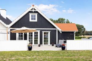 a black house with an umbrella in front of it at Cozy Central House Near The Sea in Brenderup