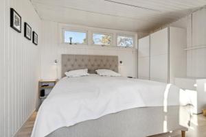 a bedroom with a large white bed with a window at Cozy Cottage Only 500 M From The Sea in Gilleleje