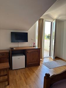 a living room with a tv and a table with a desk at Laco Rooms in Novigrad Istria +38 photos
