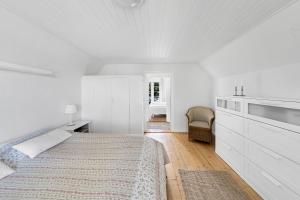 a white bedroom with a bed and a chair at Cottage With Breathtaking Sea And Cliff Views in Allinge