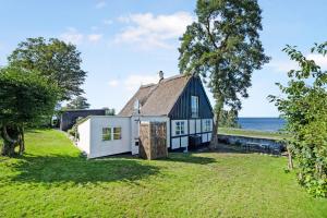 a black and white house with the ocean in the background at Cottage With Breathtaking Sea And Cliff Views in Allinge