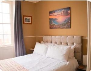 a bedroom with a white bed with a picture above it at Trillberry Guesthouse in Weymouth