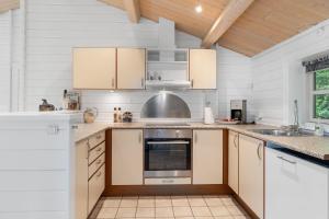 a kitchen with white cabinets and a sink at Summer Cottage With Jacuzzi And Sauna in Fakse Ladeplads