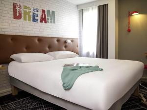 a bedroom with a bed with a green shirt on it at ibis Styles Chartres Métropole in Chartres