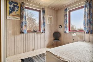 a bedroom with a bed and two windows at Spacious Cottage Surrounded By Forest in Mesinge