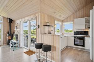a kitchen with wooden walls and white cabinets and a stove at Lovely Summer House In Haderslev in Haderslev +21 photos