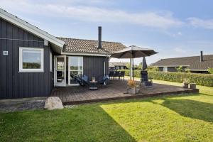 a house with a deck with an umbrella at Lovely Summer House In Haderslev in Haderslev