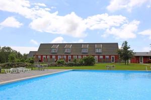 a house with a swimming pool in front of a building at Holiday Apartment For 4 With Shared Pool in Åkirkeby