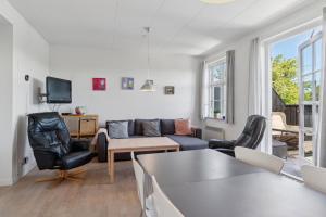 a living room with a couch and chairs and a tv at Holiday Apartment For 4 With Shared Pool in Åkirkeby