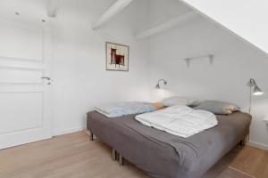 a bed in a room with white walls at Holiday Apartment For 4 With Shared Pool in Åkirkeby +18 photos