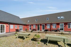 a group of red buildings with benches in a courtyard at Holiday Apartment For 4 With Shared Pool in Åkirkeby