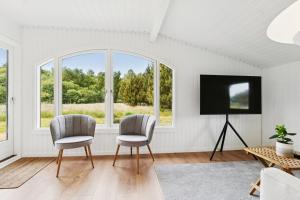 two chairs and a tv in a room with windows at Scenic Holiday Home In Bratten in Jerup