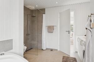 a white bathroom with a shower and a toilet at Scenic Holiday Home In Bratten in Jerup +19 photos