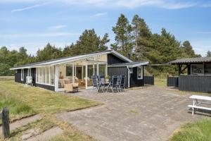a black cottage with a patio and chairs at Scenic Holiday Home In Bratten in Jerup