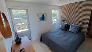 a bedroom with a bed with blue sheets and two windows at Cozy Summerhouse With Spectacular Views in Ølsted