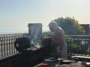 a man cooking food on a grill on a balcony at Beach View Couples Retreat Aberavon Beach Direct Seafront panoramic Sea Views large driveway parking in Port Talbot +19 photos