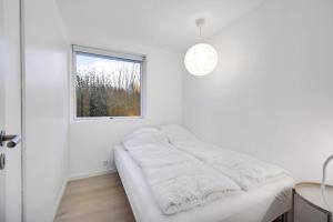 ein weißes Zimmer mit einem Bett und einem Fenster in der Unterkunft Schönes Neu Renoviertes Sommerhaus Am Meer in Frørup