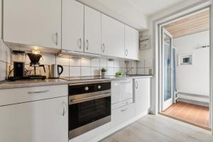 a kitchen with white cabinets and a stove top oven at Summer House On Beautiful Rømø in Sønderby +19 photos