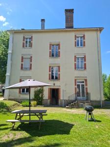 a picnic table with an umbrella in front of a building at Au Bien-hêtre in Granges-sur-Vologne