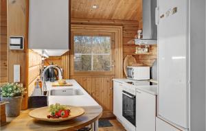a kitchen with white appliances and a table with a bowl of fruit at Cozy Log Cabin With A Panoramic View in Glesborg +25 photos