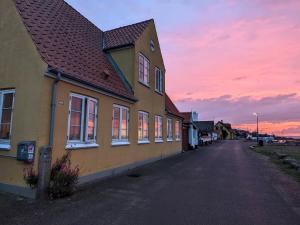 a house on a street with a sunset in the background at Lovely 2-Story Cabin By The Sea On Bornholm in Svaneke