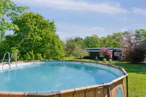 a large swimming pool in a yard with trees at Spacious Summer House With Pool in Vejby