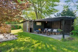 a shed with a couch and chairs in a yard at Spacious Summer House With Pool in Vejby
