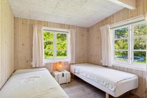 two beds in a room with two windows at Spacious Summer House With Pool in Vejby