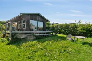 a small house with a bench in the grass at Romantic Retreat Close To The Beach in Fårevejle