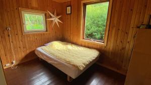 a small room with a bed and two windows at Romantic Retreat Close To The Beach in Fårevejle