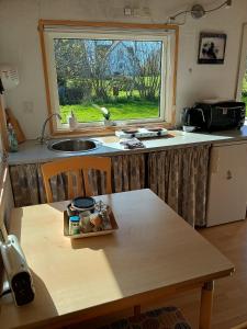 a kitchen with a table and a sink and a window at Charming Summer House In An Idyllic Area in Gylling